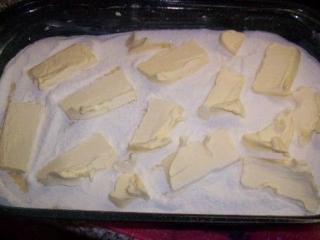Těsto si rozdělíme na dvě poloviny. Jednu polovinu vysypeme na máslem vymazaný plech, na to nalijeme tvarohovou nádivku a navrch zase sypké těsto.